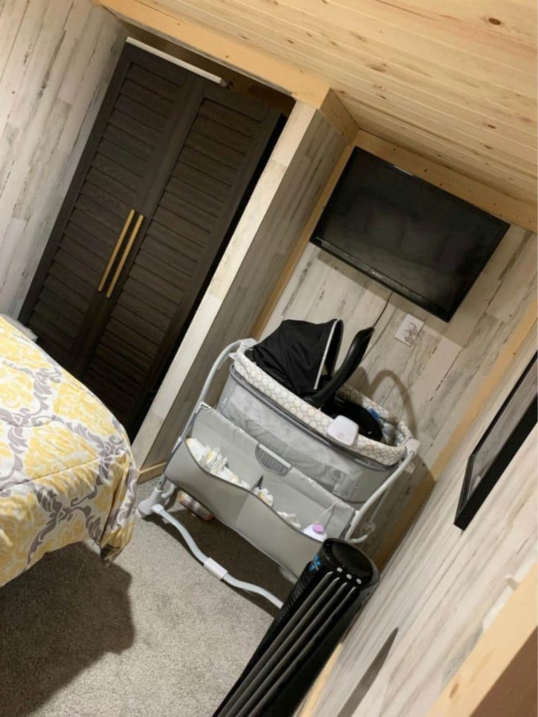 Tiny house closet with dark wood doors and corner with bassinet